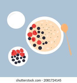 Oatmeal porridge with strawberries and blueberries. Next to it is a plate with blueberries and strawberries and a glass of milk.Delicious and healthy food for breakfast.