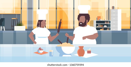 Obese Cooks Couple Preparing Tasty Meals Overweight African American Man Woman Chefs In Uniform Cooking Together Modern Kitchen Interior Restaurant Workers Team Horizontal Portrait