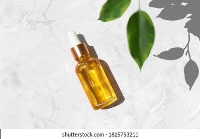 Oil serum glass bottle and defocused leaves with trendy hard shadow on luxury marble background realistic 3d vector illustration, top view. Aromatherapy oil, concept of natural cosmetic