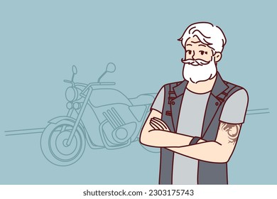 Old biker near motorcycle wishes to travel after retirement. Confident old man with tattoo on arms and gray hair is wearing biker vest for traveling around city or country on motorcycle