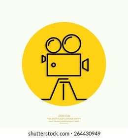 Old movie camera with reel on yellow background. Icon. 