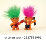 Old toy goblins, one has green hair and the other pink. One troll plays the guitar and the other plays the drums.
