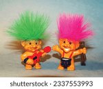 Old toy goblins, one has green hair and the other pink. One troll plays the guitar and the other plays the drums.