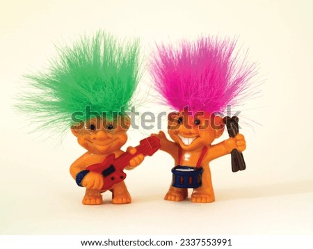 Old toy goblins, one has green hair and the other pink. One troll plays the guitar and the other plays the drums.