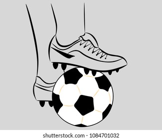 On a gray background - a white soccer ball, pressed with the feet of a football player in boots.