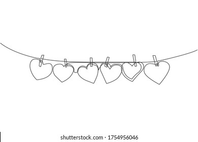 One continuous line drawing of cute heart shape paper hanged on the rope with clothesline. Romantic marriage greeting card concept. Trendy single line draw design graphic vector illustration