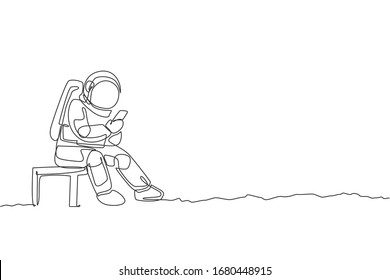 One continuous line drawing of young spaceman on spacesuit siting on chair and texting using handphone. Astronaut business office with deep space concept. Single line draw design vector illustration