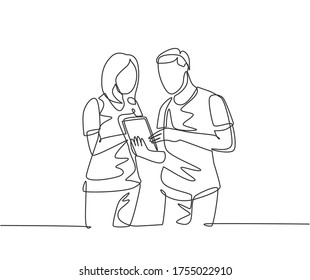 One continuous line drawing of young male and female employee talking about company target while staring tablet screen. Business goal discussion concept single line draw design vector illustration