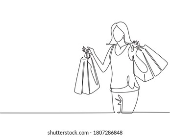 One continuous line drawing young happy beauty woman holding many paper bags after shopping personal needs. Shopping fashion, cosmetic, makeup in big mall concept. Single line draw design illustration