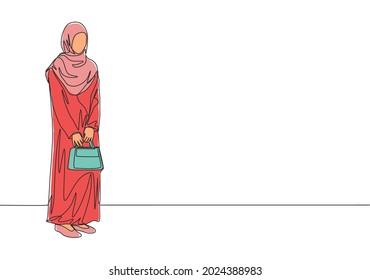 One continuous line drawing of young attractive muslimah with traditional Arab cloth holding bag. Beauty Asian woman model in trendy hijab fashion concept. Single line draw design vector illustration