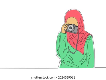 One continuous line drawing of young pretty happy muslimah with headscarf hold camera on hand. Beautiful Asian woman model in trendy hijab fashion concept single line draw design vector illustration