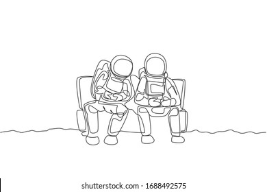 One single line drawing two young happy astronauts siting on sofa and playing video game in moon surface vector graphic illustration. Cosmonaut outer space concept. Modern continuous line draw design