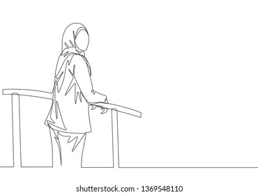 One single line drawing of young happy muslimah wearing head scarf and standing at fence. Beautiful Asian woman model in trendy hijab fashion concept continuous line draw design vector illustration