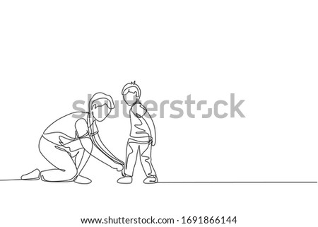 One single line drawing young father tying his son shoelaces before go to school, parenting time vector illustration. Happy family playing together concept. Modern continuous line graphic draw design