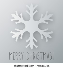 One snowflake with shadow and hand written Christmas greetings over grey background.