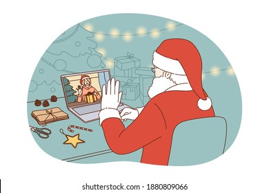 Online Christmas and New year celebration concept. Santa Claus in traditional red costume sitting and congratulating happy child with winter holidays online on laptop during video call distant meting 