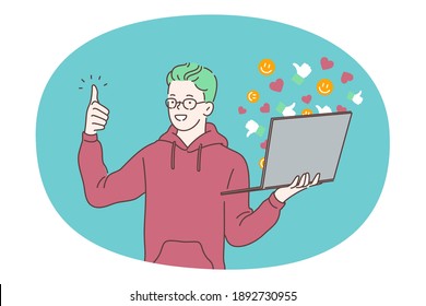 Online communication, e-learning, laptop concept. Young smiling boy standing with laptop and showing thumbs up sign with finger. Communicating online with friends, studying, watching distant courses 
