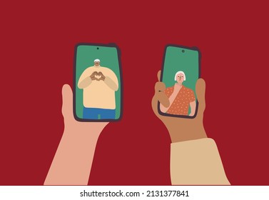 Online date, technology concept. Aged people flirt during a remote phone date. Senior man shows hands heart gesture on smartphone screen. An elderly woman sends an air kiss
