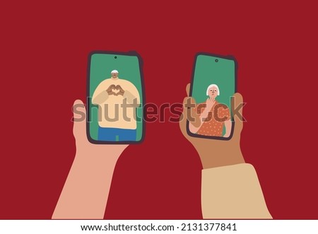 Online date, technology concept. Aged people flirt during a remote phone date. Senior man shows hands heart gesture on smartphone screen. An elderly woman sends an air kiss