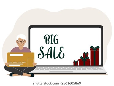 Online shopping. Big sale. A old man sits cross-legged in his hands holding a shopping card. Next to a laptop with gifts.