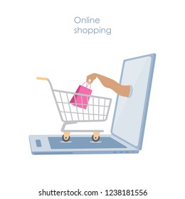 Online shopping or e-commerce concept.  Opened  laptop with a shopping cart and a hand holding a bright shopping bag
