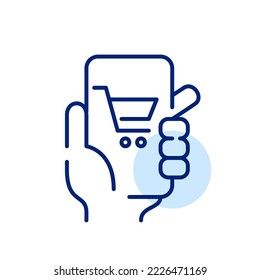 Online shopping. Hand holding smartphone with cart icon. Pixel perfect, editable stroke design