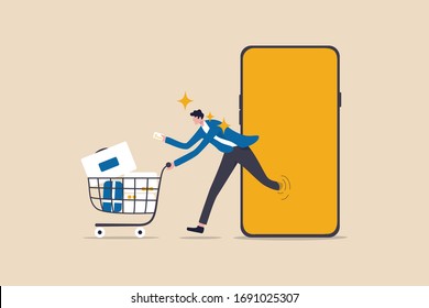 Online shopping or mobile shopping app concept, young man consumer holding credit cart pushing full of goods and box packages in shopping cart trolley running from website or app on mobile smart phone