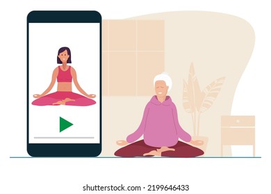 Online yoga. Elderly woman sitting in lotus position doing meditation on mat at home. Woman watches at yoga lessons on your phone. Yoga, meditation, relax, recreation, healthy lifestyle in old age