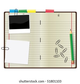 Open copybook with a green pencil, photograph and paper clips.