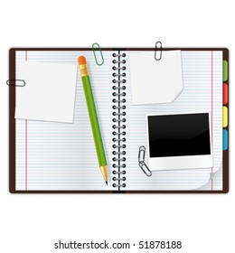 Open copybook with a green pencil, photograph and paper clips.