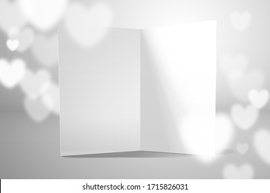An open white empty postcard stands on the surface. There are blurry hearts in the air. Template for Valentine's Day greetings, wedding invitations or declarations of love