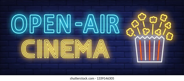 Open-air cinema neon text with popcorn paper box. Entertainment concept, advertisement design. Night bright neon sign, colorful billboard, light banner. Vector illustration in neon style.