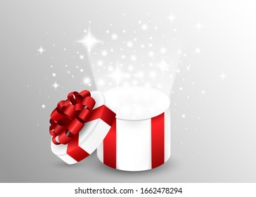 Opened gift box with red ribbon and bow. Light out of the box. Round shaped gift box.