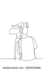 operator stands in front of the camera and looks at the screen - one line drawing. professional cinema or TV operator in the process of shooting 