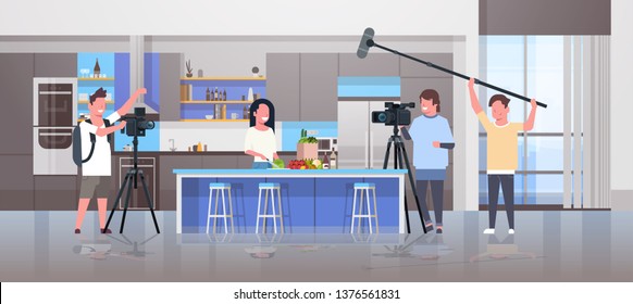 operadores con cámara de vídeo grabar bloguera de comida preparar platos sabrosos videografos con equipo profesional cocinar blog de producción de películas cocina interior horizontal