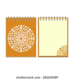 Orange cover notebook with ornate white round pattern and same design element on the pages. Isolated on white background