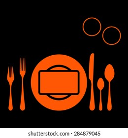 Orange plate with spoon, knife and fork on a black background