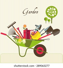 Organic farming. Wheelbarrow with tools to work in the garden. Adaptations for planting, digging up the ground, irrigation, fertilizer, spraying, weed control. Fruit tree.