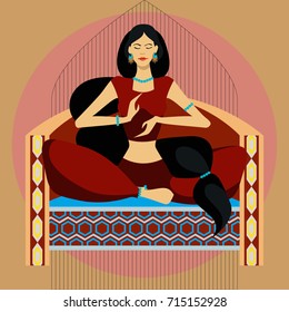 Oriental beauty sitting on the couch in lotus position on a complex colored and ornamental background