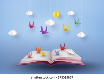origami made colorful paper bird flying over open book and  blue sky with cloud . paper art and  digital craft style. 