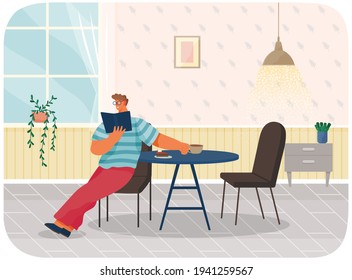 oung stylish man in glasses reading book sitting at home at table eating cake, drinking coffee