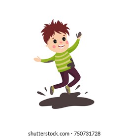 Overactive kid in soiled sweater and pants jumping in mud puddle
