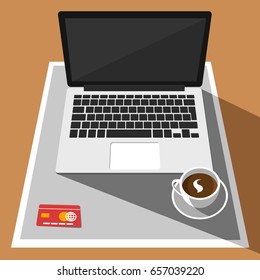 Overhead view of laptop, credit card and a cup of coffee on a desk