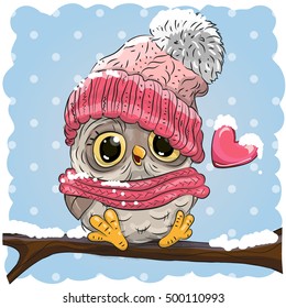 Owl in a knitted cap sits on a branch in a snow