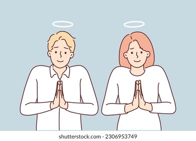 Pair of angels pray with hands folded in front of chests and standing with halo over heads. Man and woman with halos of angels are asked to be more merciful and show compassion for people.