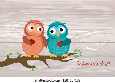A pair of cute owlet sitting on a branch. Owls in love hold hearts for each other. Greeting card for Valentine's Day. Vector illustration on wooden background.