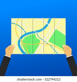 A pair of hands holding folded paper map.