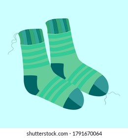 a pair of knitted warm striped turquoise socks with protruding threads on a blue background