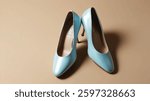 A pair of light blue, pointed-toe high heels are displayed on a beige background. The shoes are angled, showing their sleek design and stiletto heels.