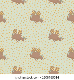 Pale seamless cinema pattern with cameras. Stylized ornament in beige tones on light grey dotted background. Backdrop for wallpaper, textile, wrapping paper, fabric print. Vector illustration.